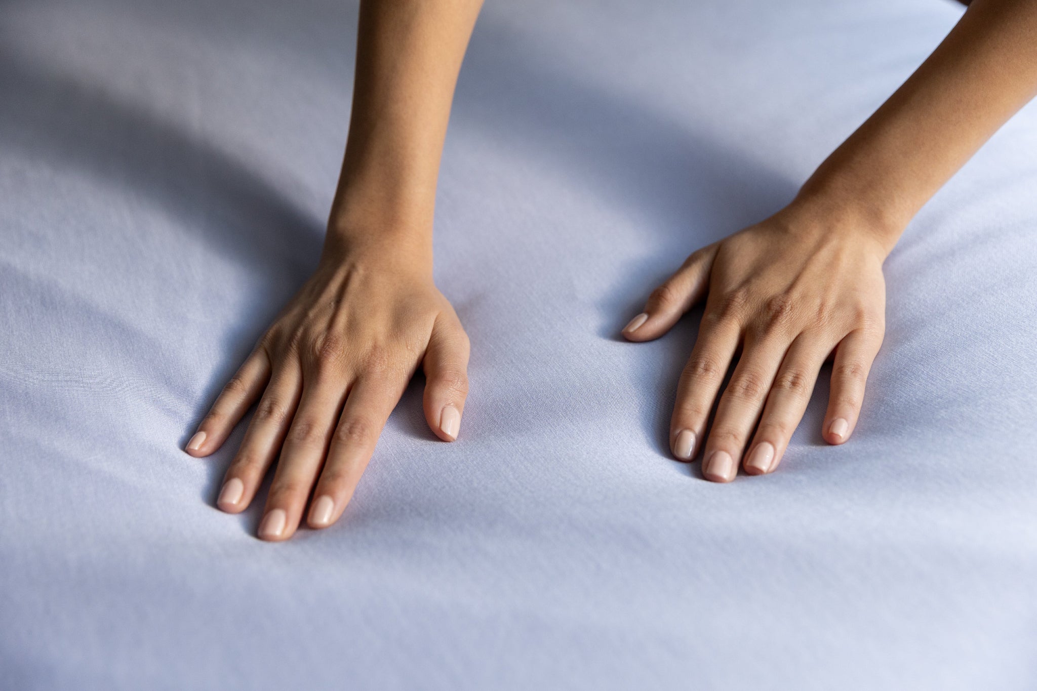 Two hands resting on a light blue jersey knit fabric