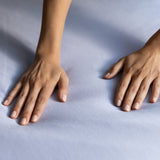Two hands resting on a light blue jersey knit fabric