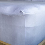 Close-up of a light blue fitted sheet on a bed with wooden frame