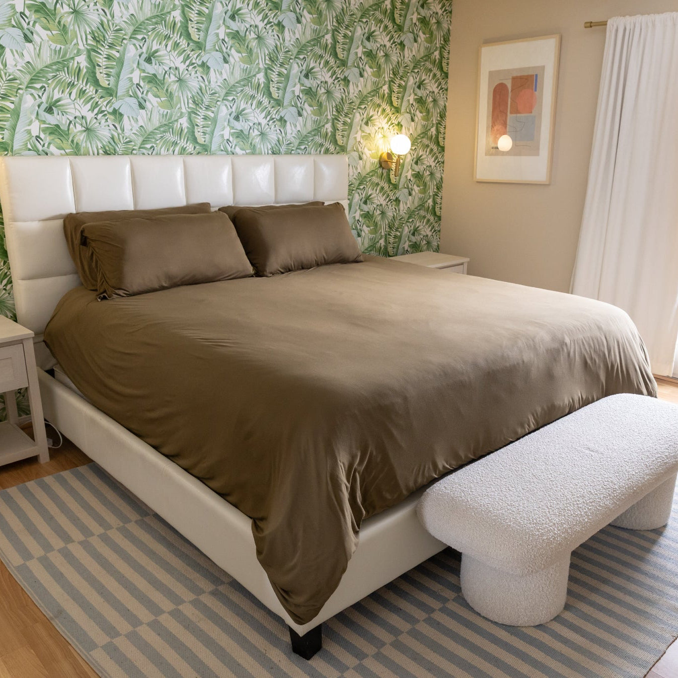 Bedroom with a bed, footstool, and palm wallpaper