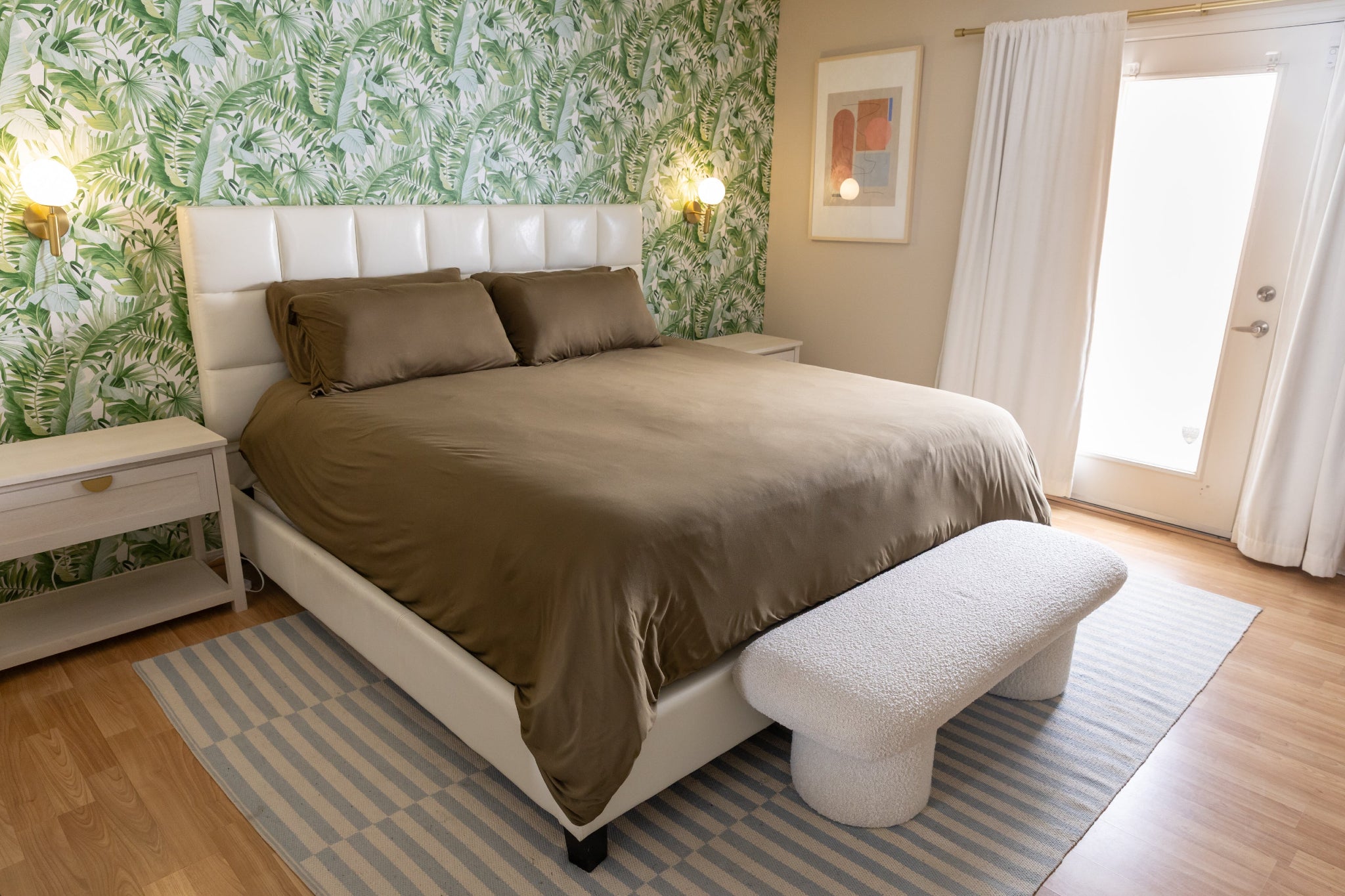 Bedroom with a bed, footstool, and palm wallpaper