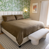 Bedroom with a bed, footstool, and palm wallpaper