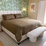 Bedroom with a bed, footstool, and floral wallpaper