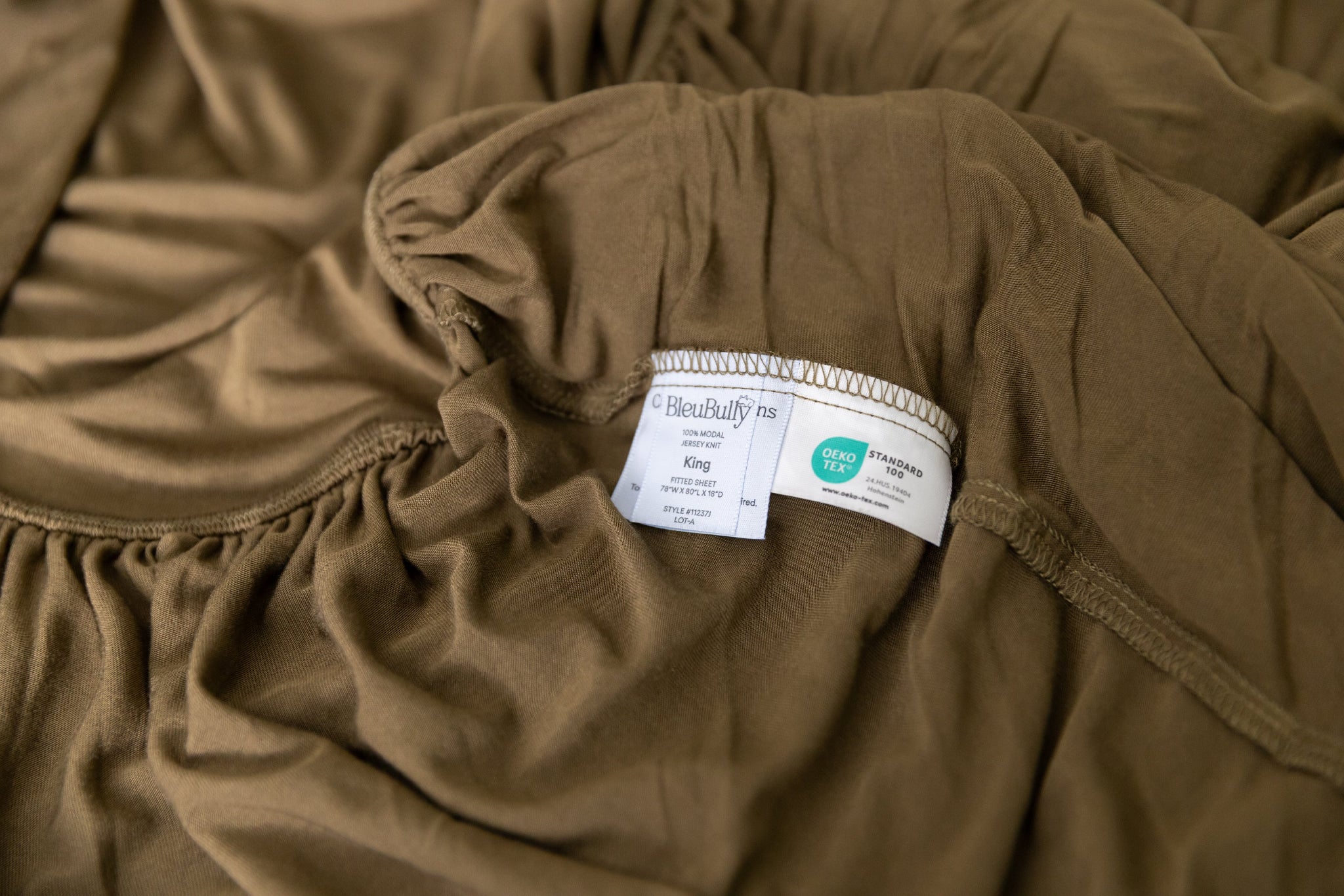 Brown fitted sheet with a tag on a bed