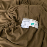 Brown fitted sheet with a tag on a bed