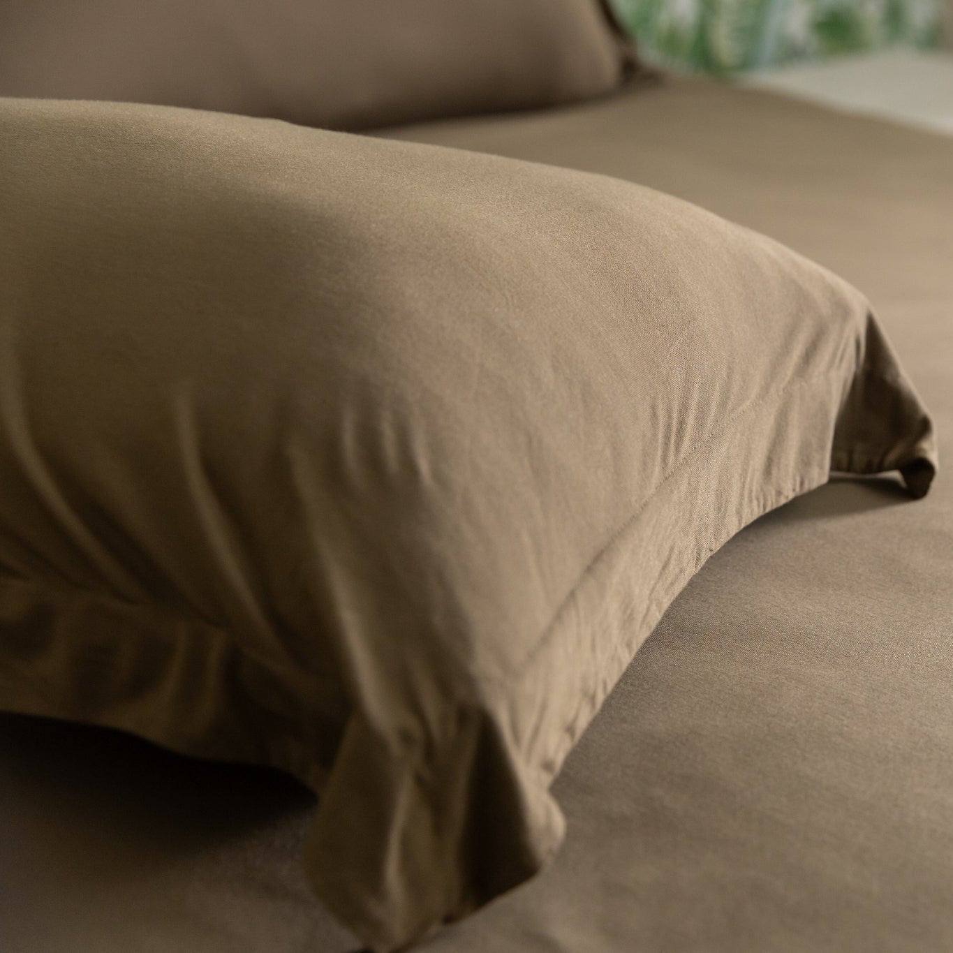 green pillow sham on a bed with a blurred background