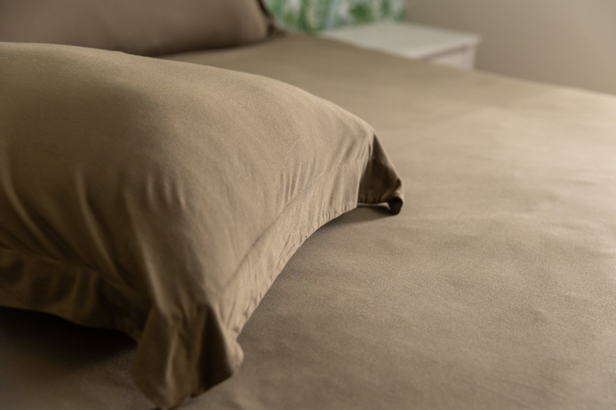 green pillow sham on a bed with a blurred background