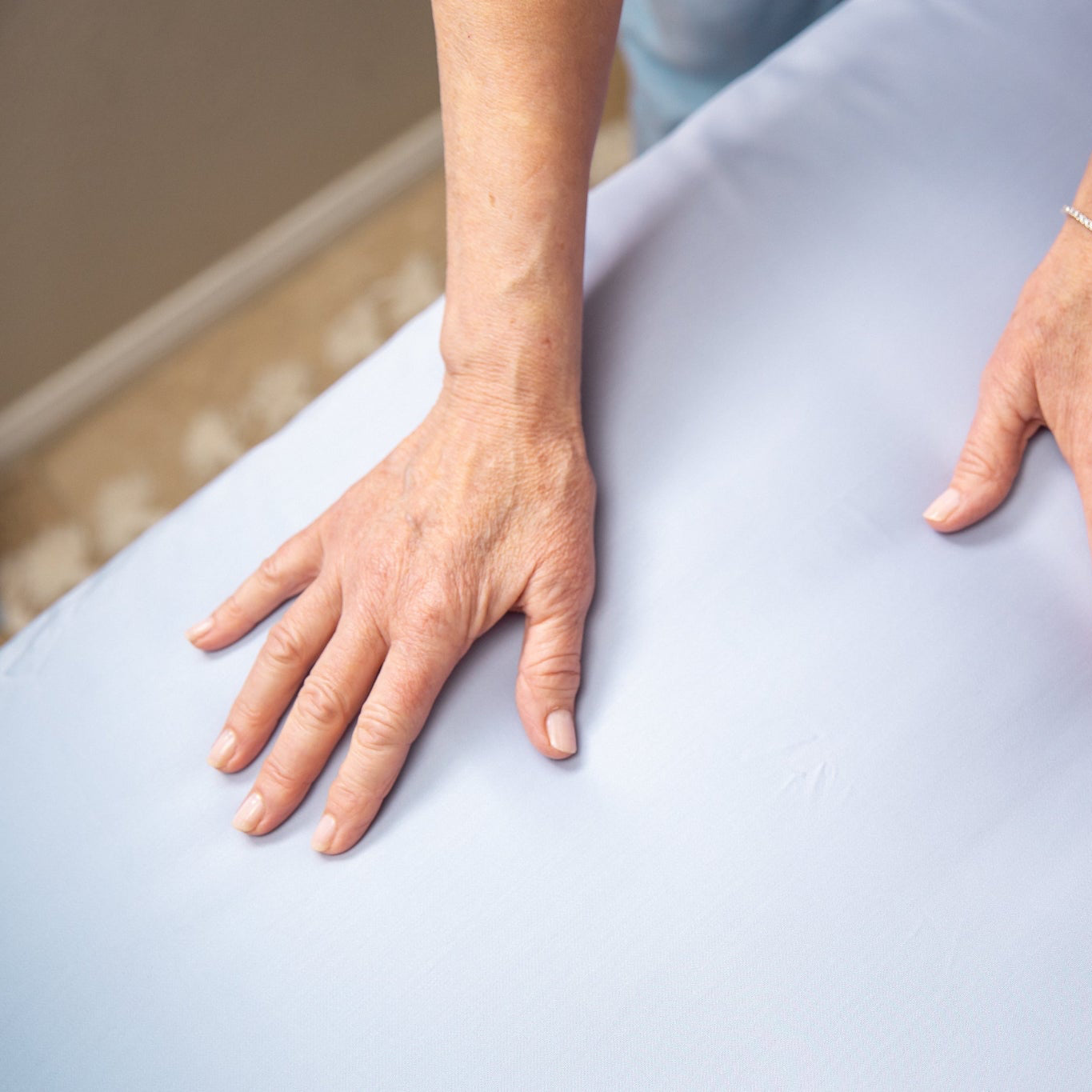 Close-up of a person's hands on a light blue fabric