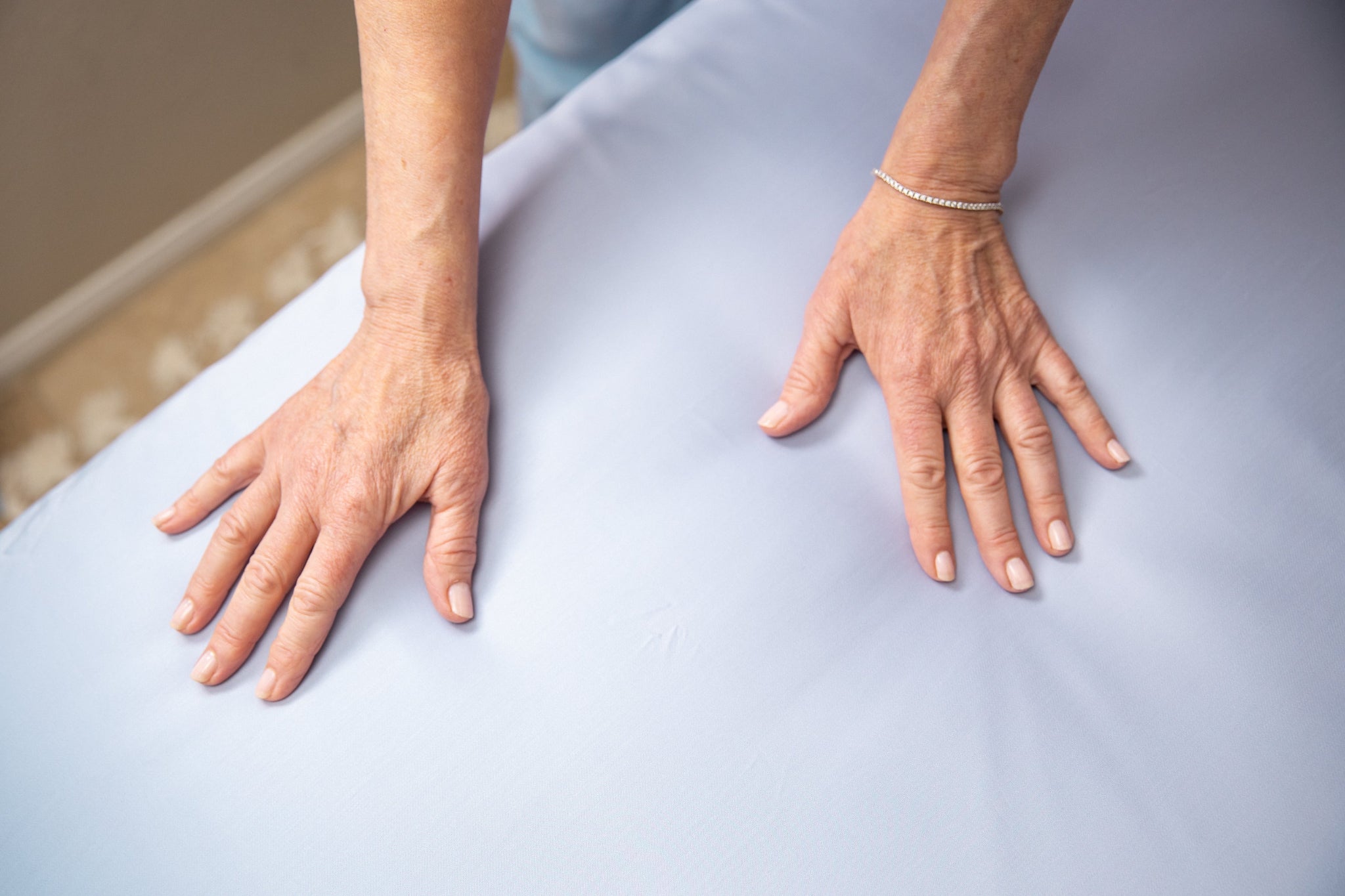 Close-up of a person's hands on a light blue fabric