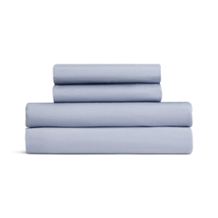 Set of light blue bed sheets stacked on a white background