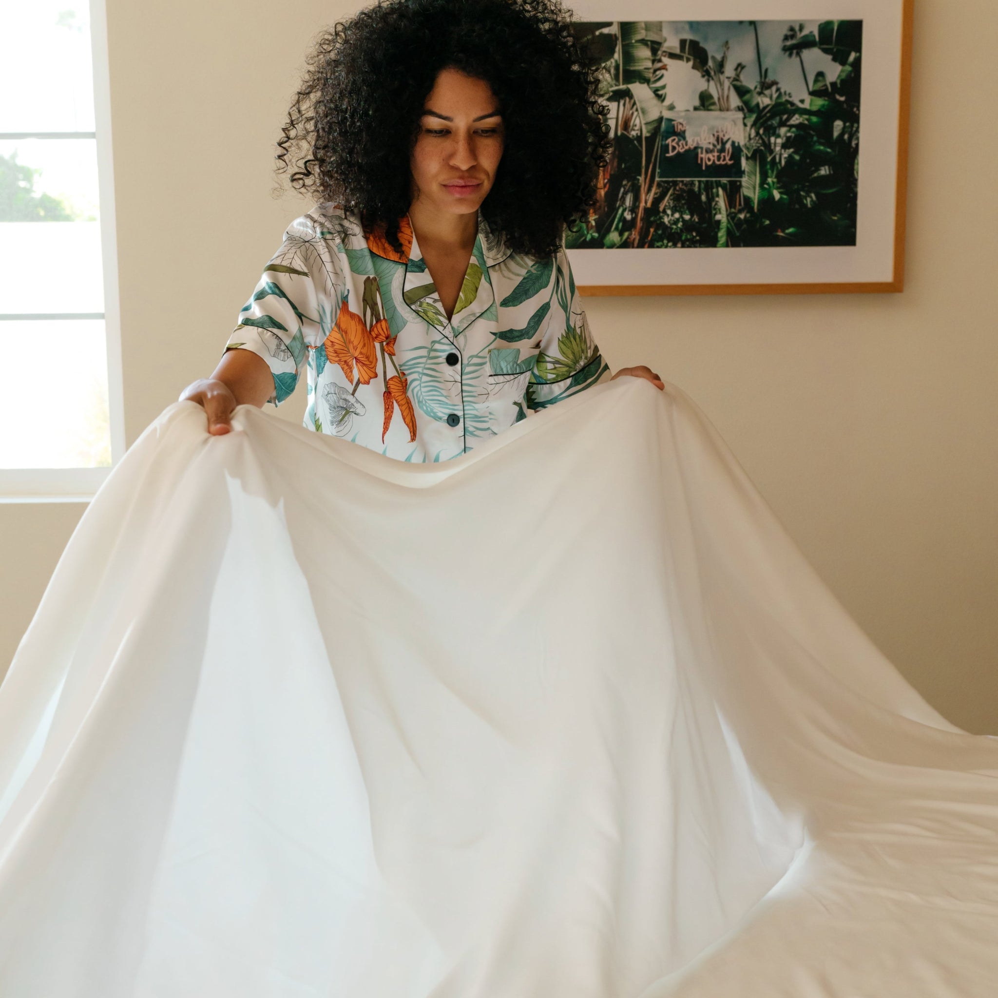 A person presenting an ivory white sateen sheet set, displaying the fabric's texture and color.