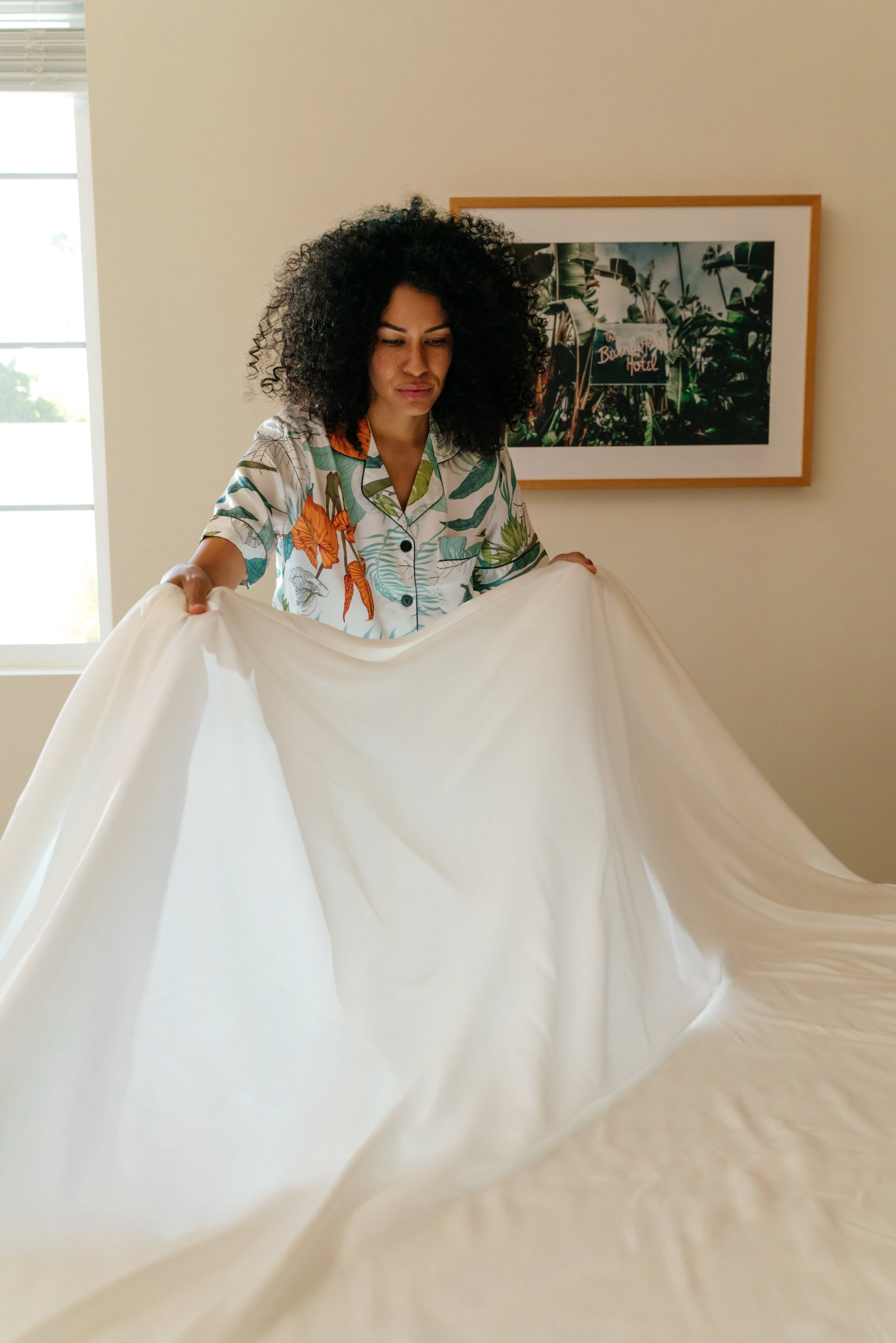 A person presenting an ivory white sateen sheet set, displaying the fabric's texture and color.